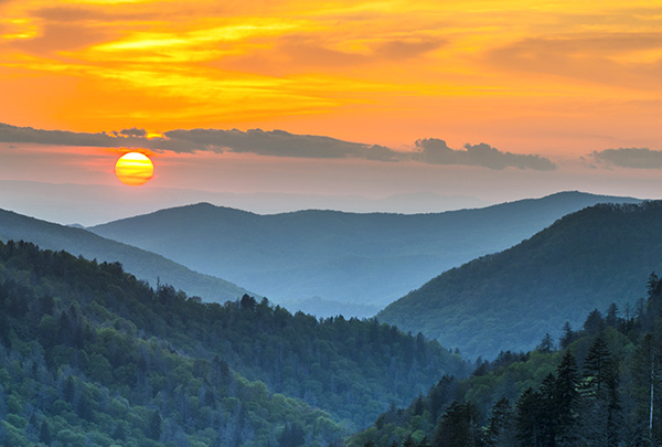 Photo of sunset over blue mountains.