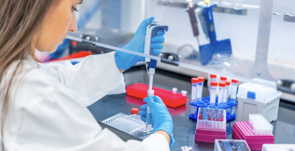 Technician working under a safety hood with a pipette.